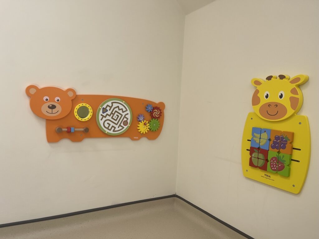 A bright, child-friendly waiting area at The Watermill Clinic with wall-mounted activity toys, helping young patients feel comfortable and relaxed.